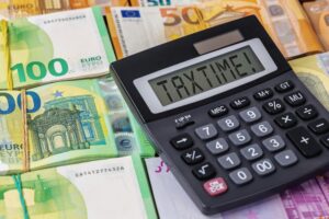 Calculator,With,Text,Taxtime,On,Screen,Lying,On,Euro,Banknotes.
